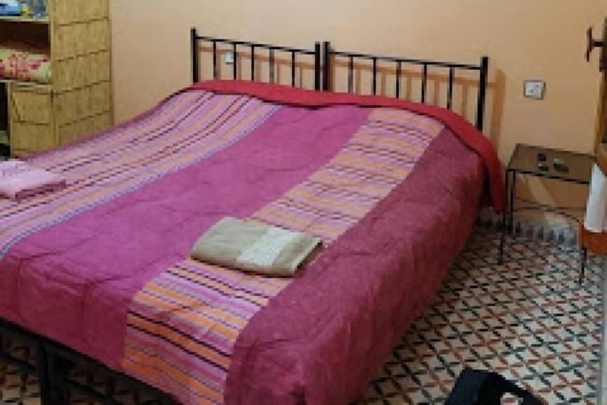 Ein Schlafzimmer mit einem Bett, einem Holzschrank, einem kleinen Tisch und einem an der Wand befestigten Regal.