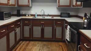 A kitchen with wooden cabinets, a microwave, a toaster, and a sink.