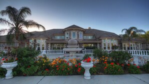 A large, two-story house with a stone facade, multiple windows, and a central fountain. - Paradise Vacation Estate - Largest Luxury Private Vacation Resort (Temecula)
