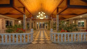 A spacious lobby with a checkered floor, a central chandelier, and stone pillars. - Paradise Vacation Estate - Largest Luxury Private Vacation Resort (Temecula)