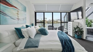 Un dormitorio moderno con una cama grande, vistas a la ciudad, un televisor de pantalla plana y una escalera.
