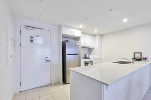 A modern kitchen with white cabinetry, a stainless steel refrigerator, and a white countertop. - Darwin City Harbour Views-above the Oak Restaurant (Darwin City)