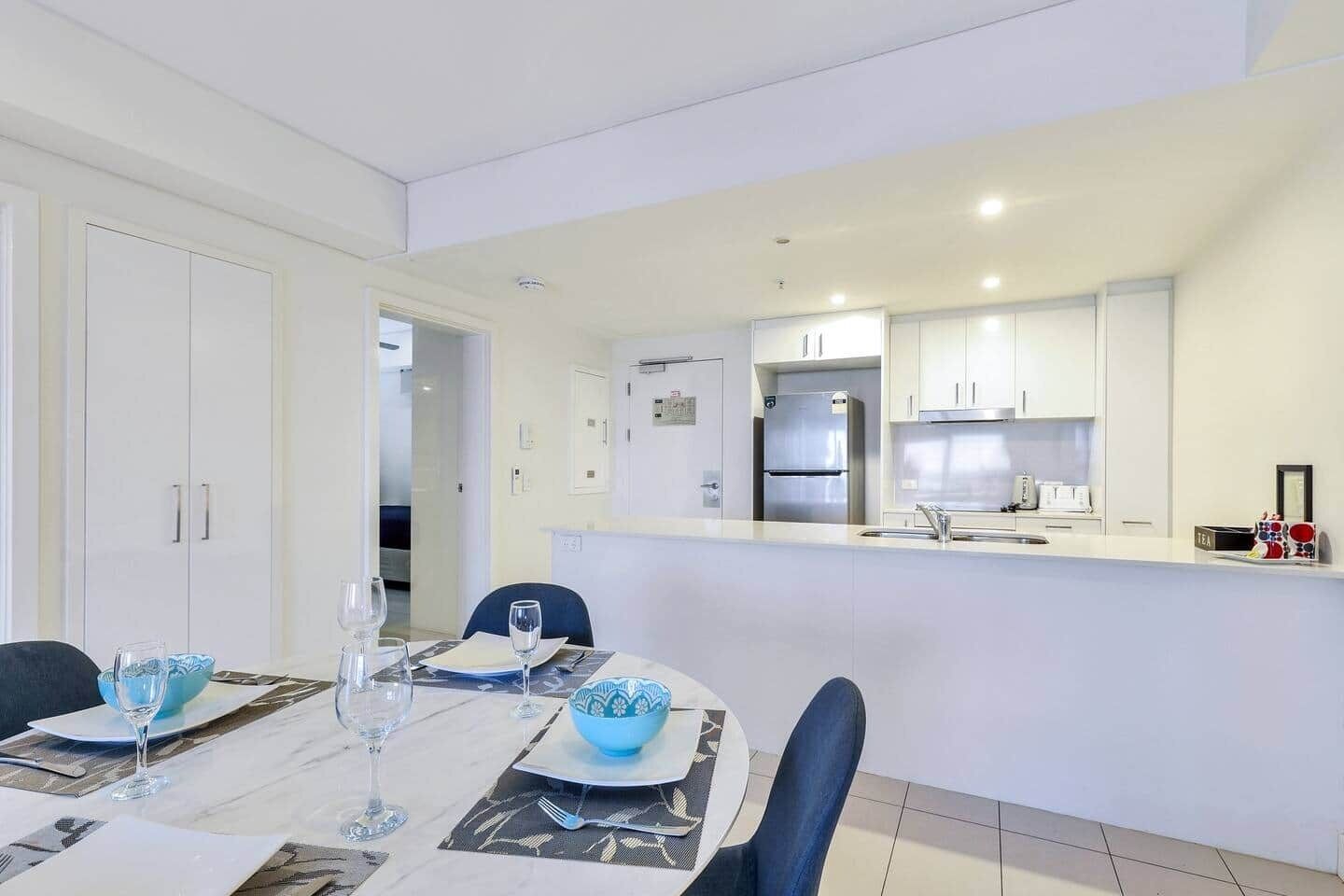 A modern kitchen with white cabinets, a stainless steel refrigerator, and a countertop with a sink.