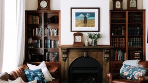 Uma sala de estar aconchegante com lareira, sofás de couro e estantes de madeira repletas de livros.