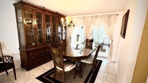 Comedor con un aparador de madera, una mesa con cubierta de vidrio y sillas.
