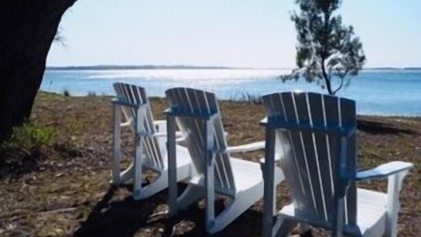 Three Adirondack chairs with a view of the water.