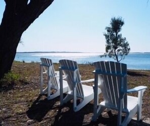 Drie Adirondack stoelen met uitzicht op het water.