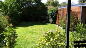 A well-maintained garden with a lawn, various shrubs, and a wooden fence. - Bring the Dog, Bring the Boat, Bring the Family (Burrill Lake)