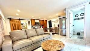 A modern living room with a leather sofa, a round coffee table, and a kitchen in the background.