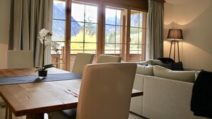 A room with a wooden dining table, a sofa, and a lamp.