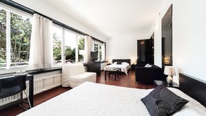 Una habitación de hotel moderna con una cama grande, un escritorio, una silla, una mesita y un televisor.