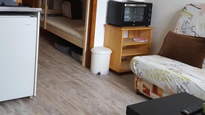 A compact room with a bunk bed, a small kitchenette, a microwave, and a single bed with a floral bedspread. - STUDIO 17m², 5 BEDS (Les Orres)