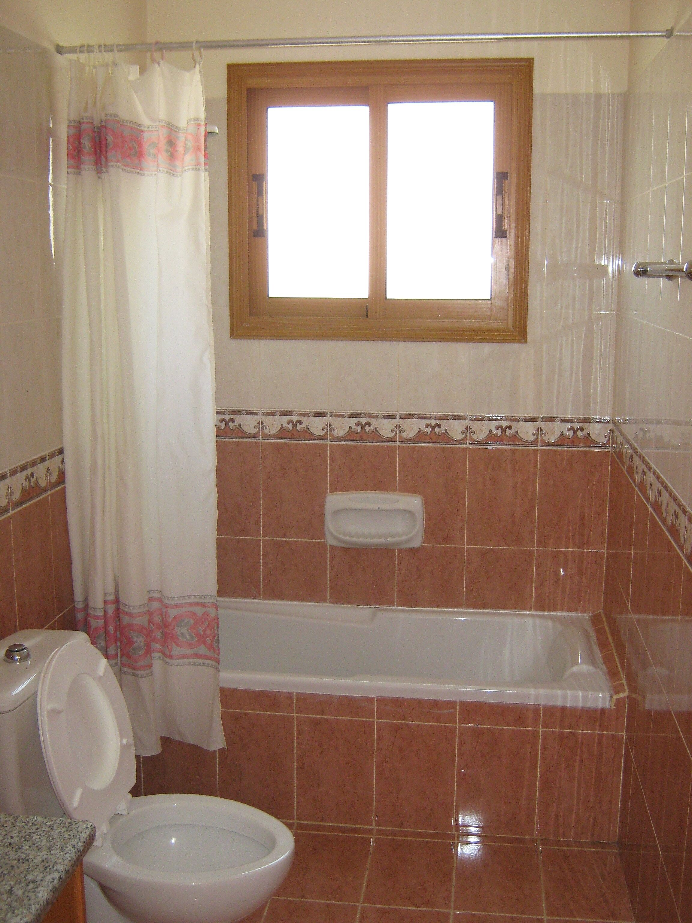 A bathroom with a toilet, a bathtub, and a window.