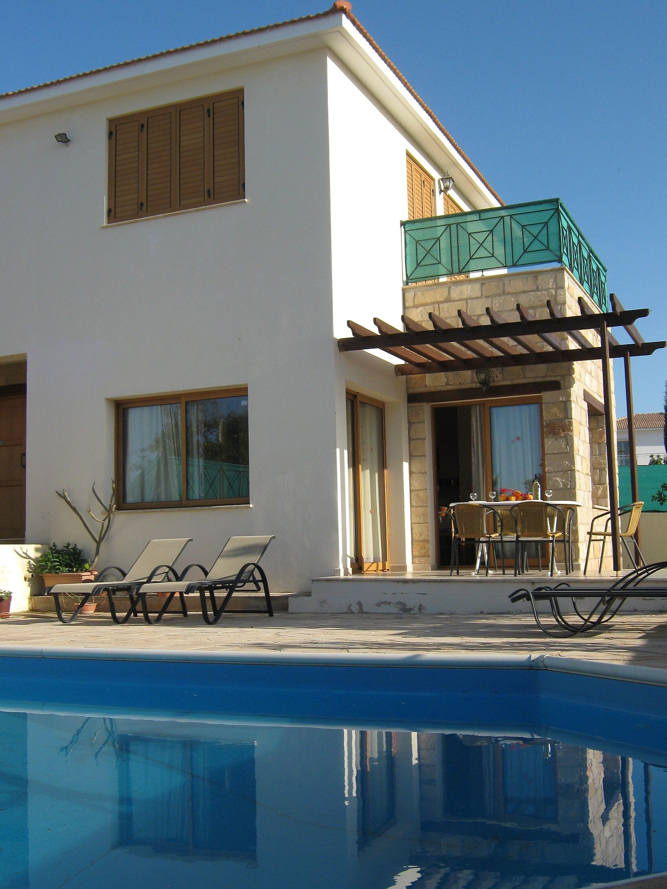 A two-story house with a pool, outdoor seating, and a balcony.