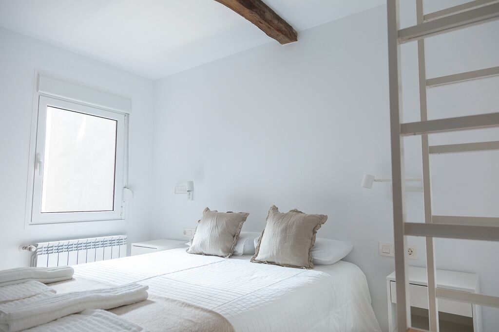 A bedroom with a large bed, two pillows, a radiator, and a window.