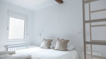 A bedroom with a large bed, two pillows, a radiator, and a window.