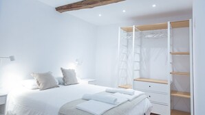 A bedroom with a bed, bedside tables, a wardrobe, and a ceiling with exposed beams. - SAN SEBASTIAN TRAIN & BUS STATION TOURIST FLAT (DONOSTIA)