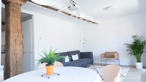 A modern living room with a grey sofa, a round table with a white tablecloth, and a potted plant. - SAN SEBASTIAN TRAIN & BUS STATION TOURIST FLAT (DONOSTIA)