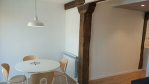 A dining area with a round table and four chairs, a hanging light fixture, and exposed wooden beams. - SAN SEBASTIAN TRAIN & BUS STATION TOURIST FLAT (DONOSTIA)