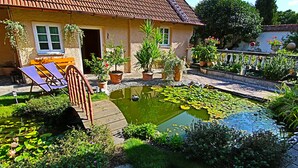 Ein Haus mit einem Gartenpond, einer Holzterrasse und einer Bank.
