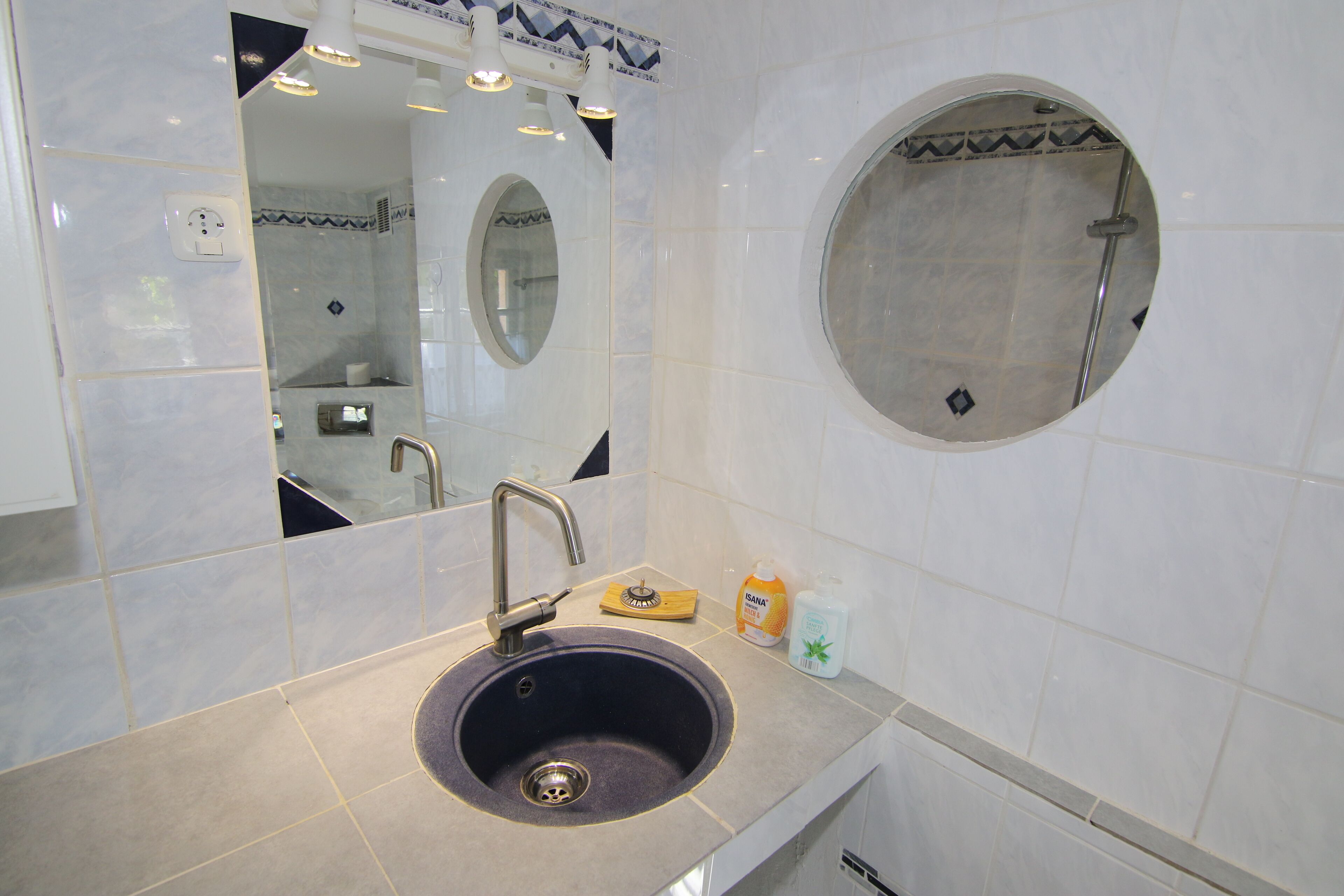 A bathroom with a sink, mirror, and round shower.