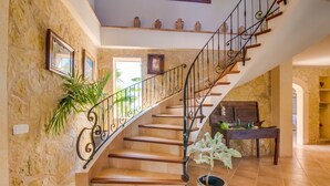 Eine Treppe mit schmiedeeisernem Geländer, Holzstufen und einem Blumentopf am Fuß.
