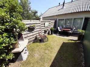 A backyard with a wooden fence, a table and chairs, and potted plants.