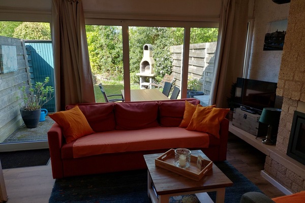 renoviertes Wohnzimmer mit TV, geschlossenem Kamin und Terrasse mit Garten