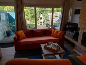 Un salon avec un canapé rouge, une table basse en bois, un téléviseur et une cheminée.