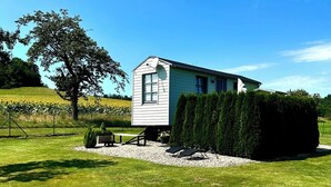 A small, single-story house with a sloped roof, a window, and a door, surrounded by a well-maintained lawn and a large tree. - Harz vacation under the apple tree  (Cattenstedt)