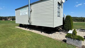 A small, single-story building with a satellite dish and a chimney, situated on a grassy field with a clear sky. - Harz vacation under the apple tree  (Cattenstedt)