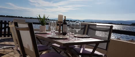 An outdoor dining table with chairs, a candle, wine glasses, and a potted plant.