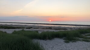 A beach with sand and grass in the foreground, and the ocean in the background. - Last-Minute Summer Deals! A vacation right on the beach! (Neuharlingersiel)