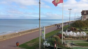 En kystpromenade med en café, 'Café du Golf', og et flagstang med flag.