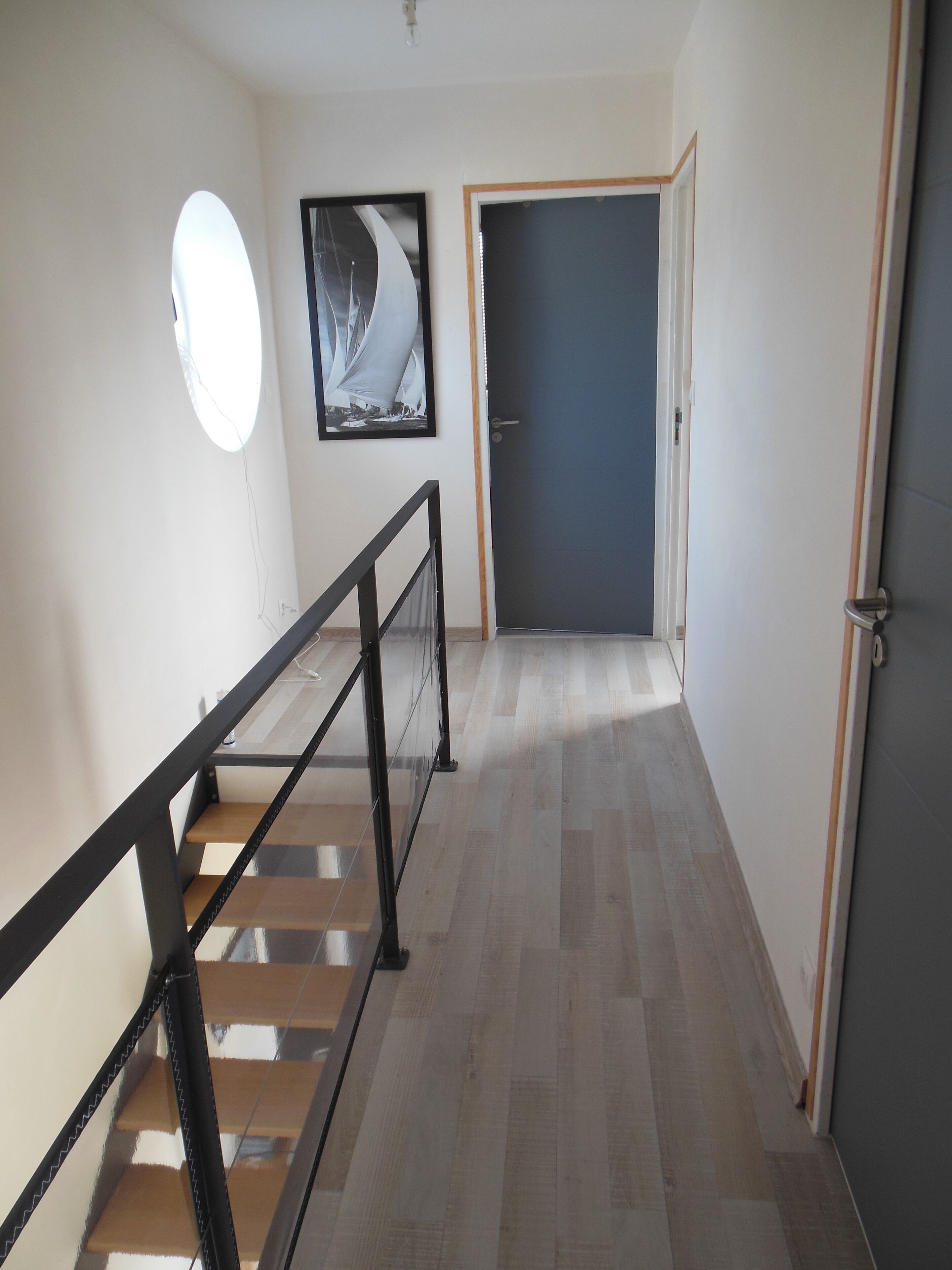Ein Flur mit einer Holztreppe, einem gerahmten Bild an der Wand und einer Tür am Ende.