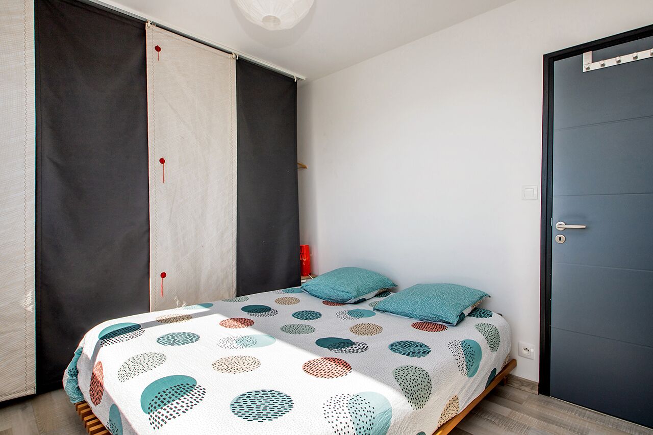 A bedroom with a bed, pillows, a wardrobe, and a door.