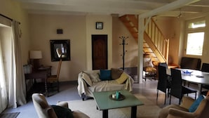 A living room with a sofa, two armchairs, a coffee table, and a staircase leading to another room. - Nestled in a wooded park, with the beach just 3 minutes away (Pénestin)