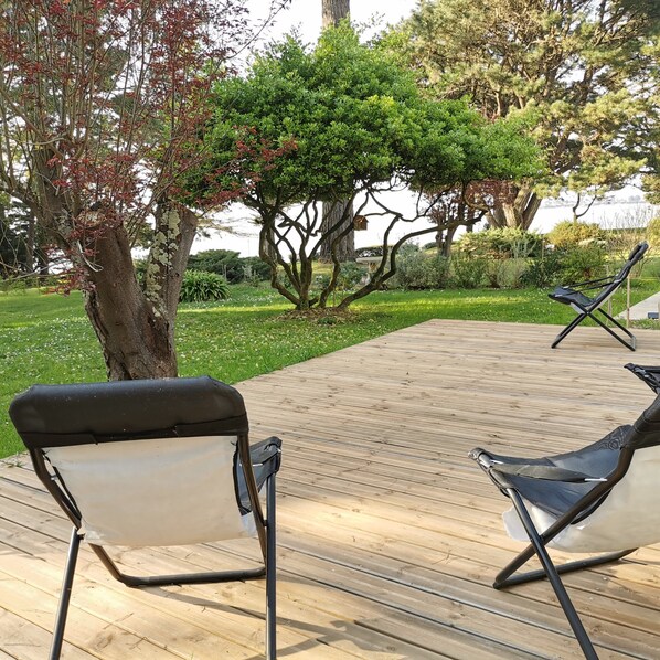 A wooden deck with two black and white lounge chairs.