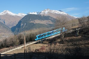 Un train bleu sur un pont, avec des montagnes enneigées en arrière-plan.