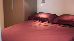 Une chambre à coucher comprenant un lit, une armoire et un luminaire fixé au mur.
