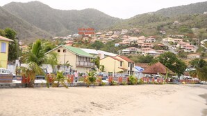 A coastal town with buildings on a hillside, a sandy beach, and palm trees. - Villa Standing - Beaches at 400 meters - Swimming Pool (ANSES D'ARLET)