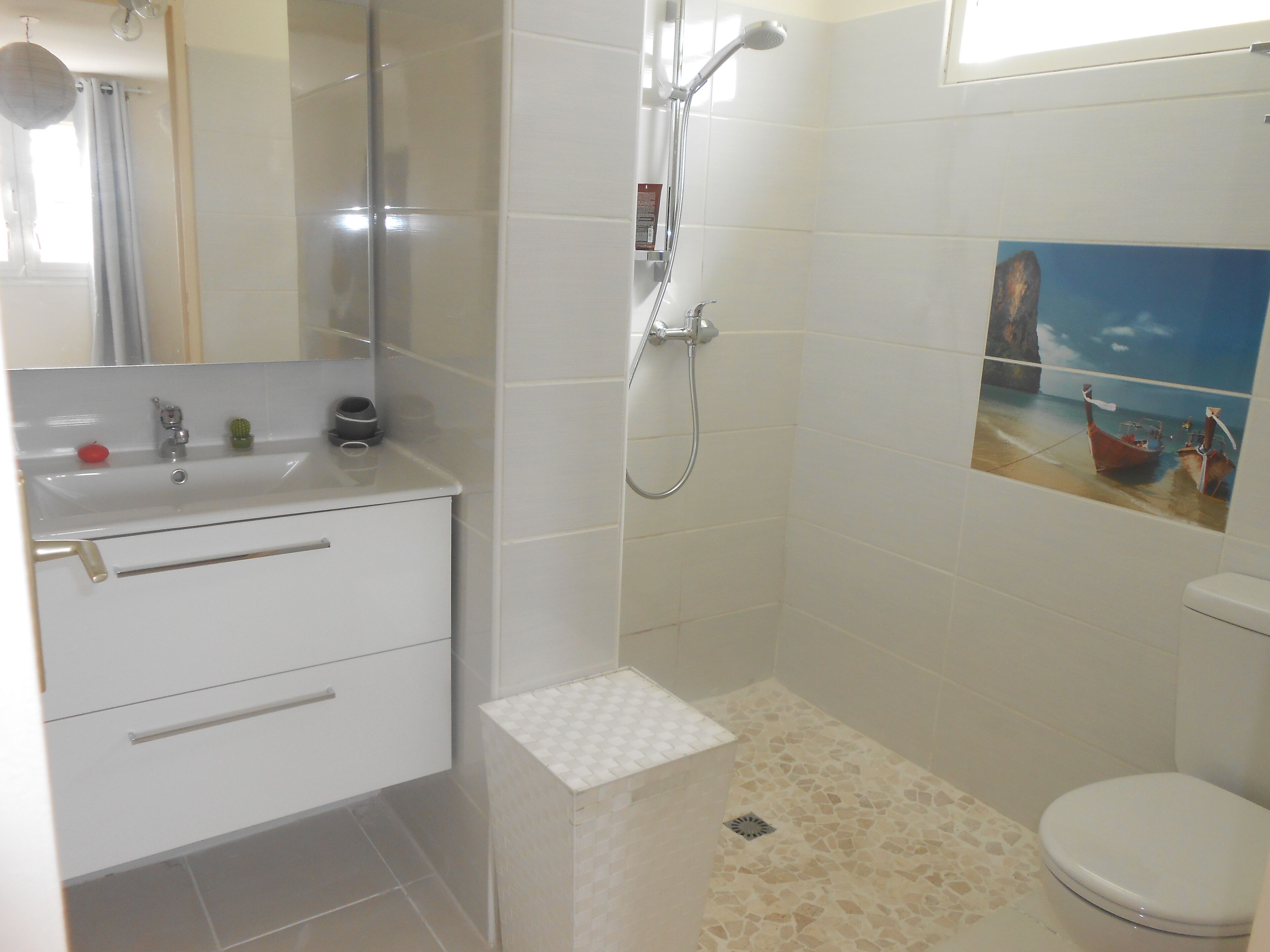 A bathroom with a shower, toilet, sink, and a decorative painting on the wall.