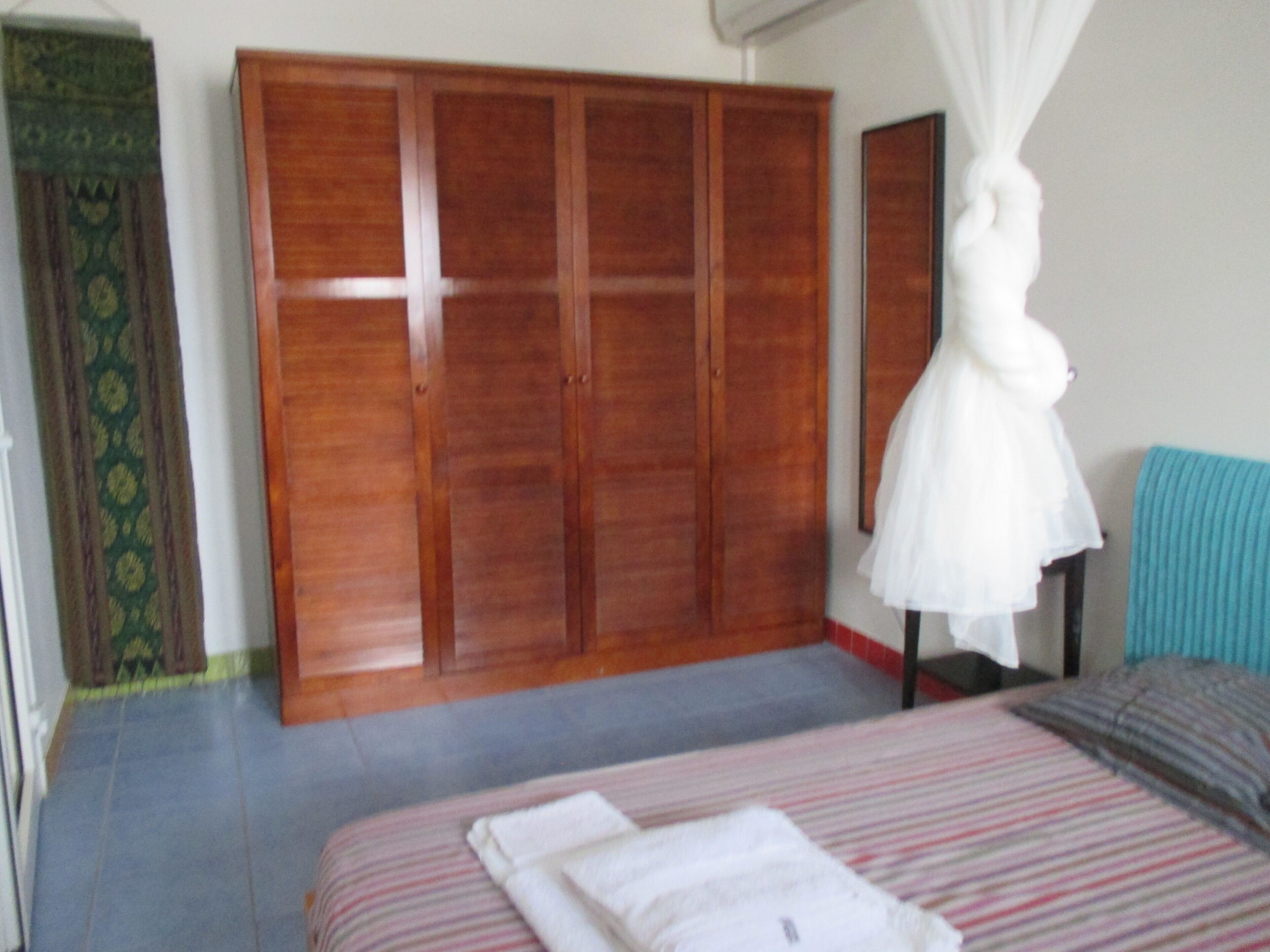 Une chambre à coucher avec un lit, une armoire, un rideau et un fauteuil suspendu.