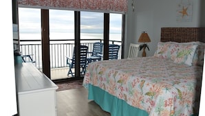 A bedroom with a balcony, a bed with floral bedding, a lamp, and a starfish decoration. - Beautiful Ocean and Inlet Views From This Newly Updated Corner Unit (North Myrtle Beach)