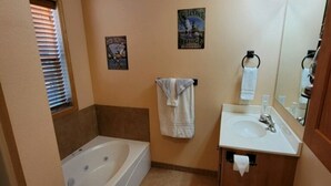 Une salle de bain équipée d’une baignoire, de toilettes, d’un lavabo et d’un miroir.