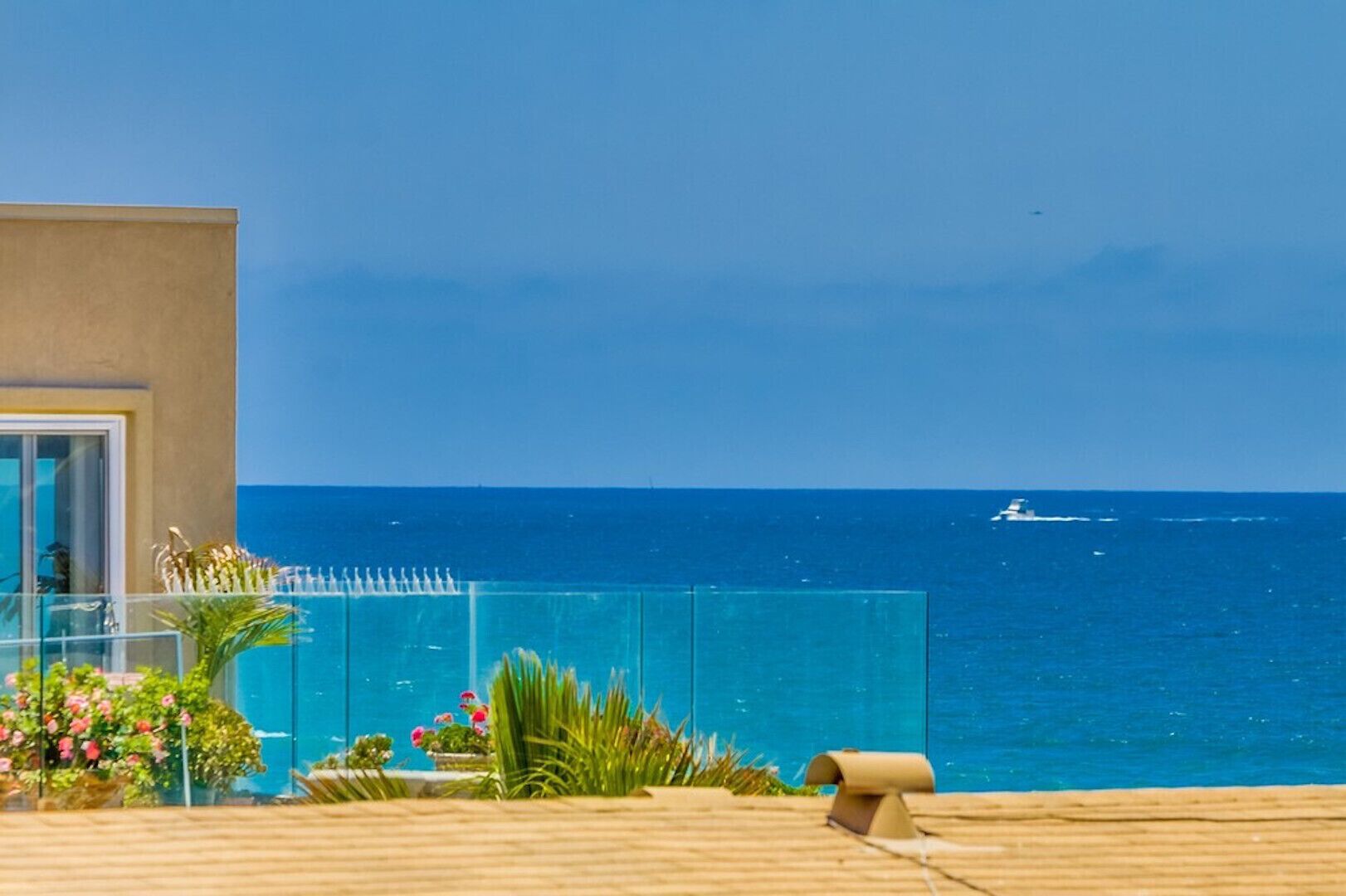 Un balcone con vista libera sull'oceano e una barca all'orizzonte.