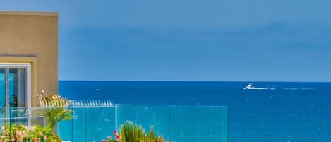 Un balcone con vista libera sull'oceano e una barca all'orizzonte.