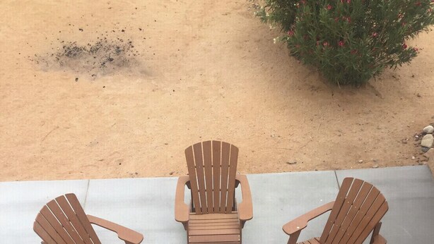 Un espacio de descanso al aire libre circular con seis sillas Adirondack y un hogar central.