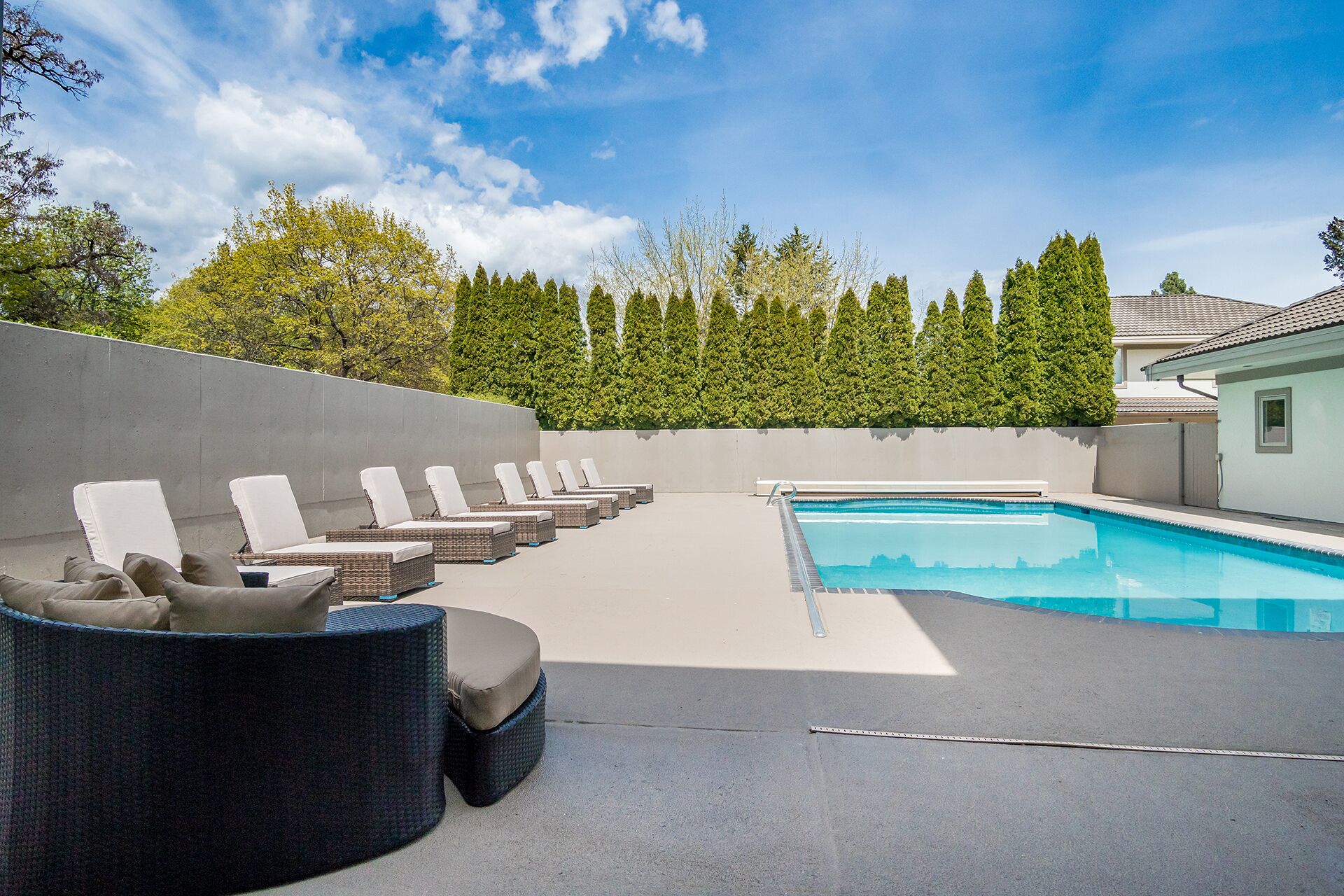 Zona junto a la piscina con sillones de descanso y una piscina.