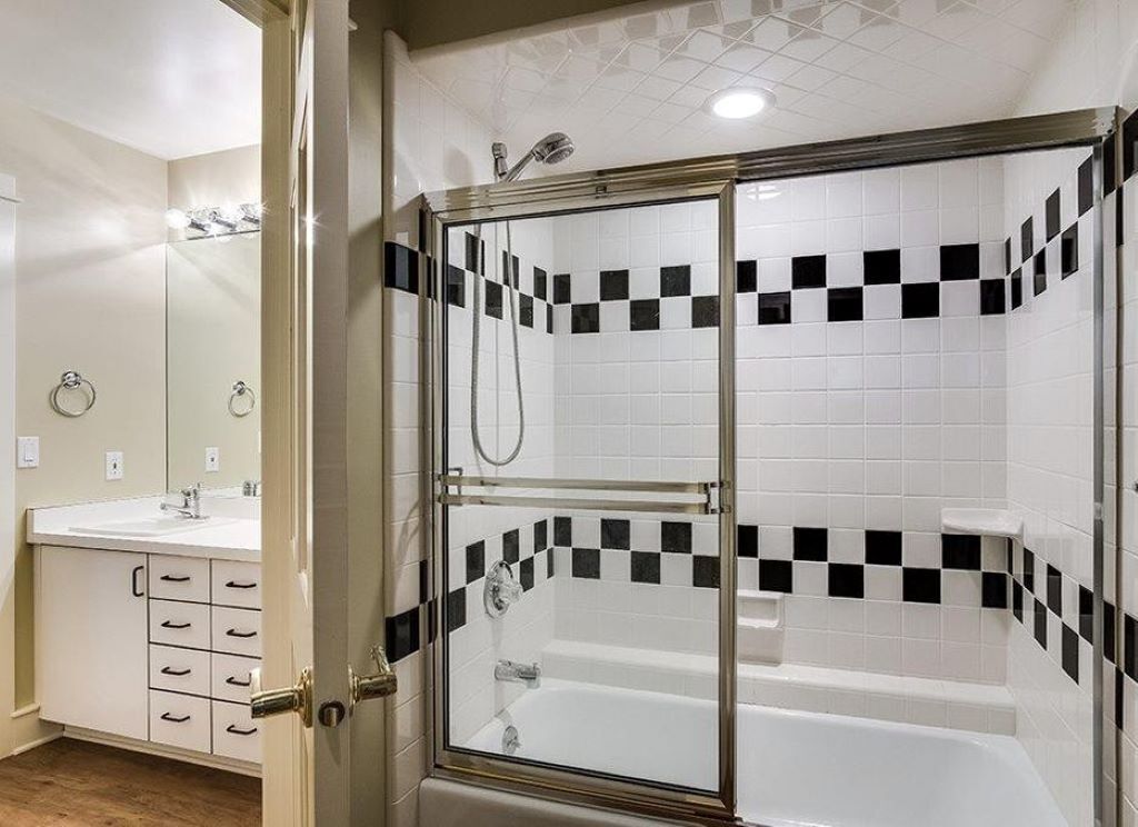 A modern bathroom with a glass-enclosed shower, a white sink, and a mirror.
